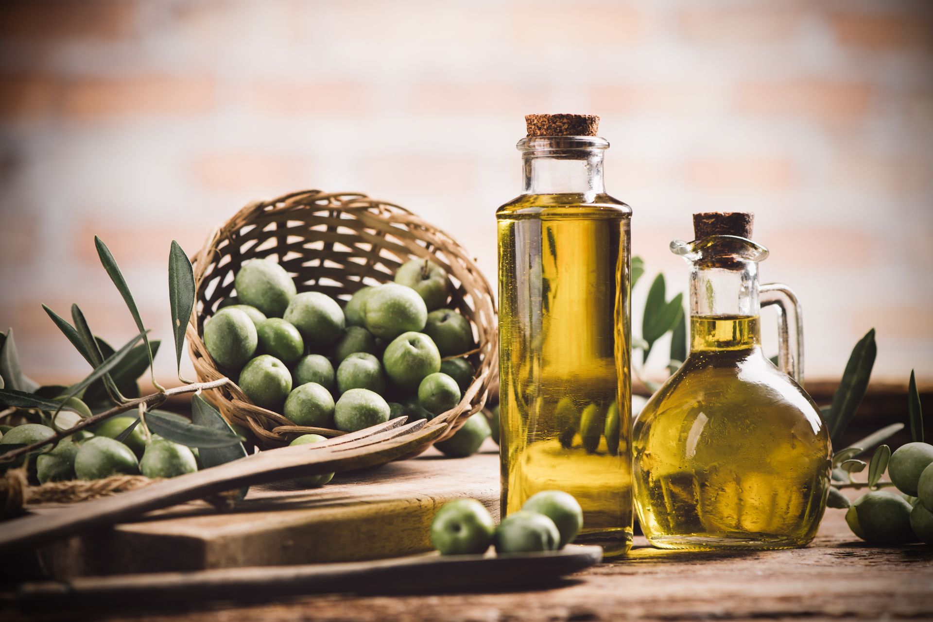 Bouteilles d'huile d'olive avec des olives vertes et des branches sur une table rustique