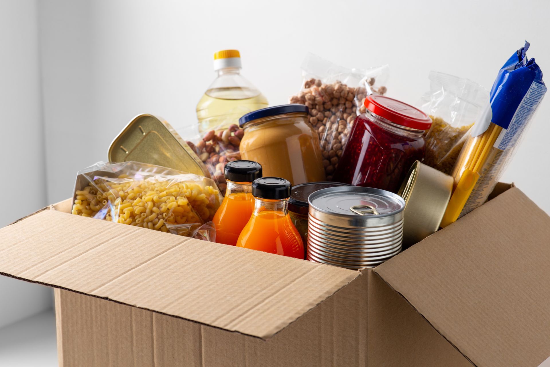 Boîte en carton remplie de conserves et d'aliments emballés assortis