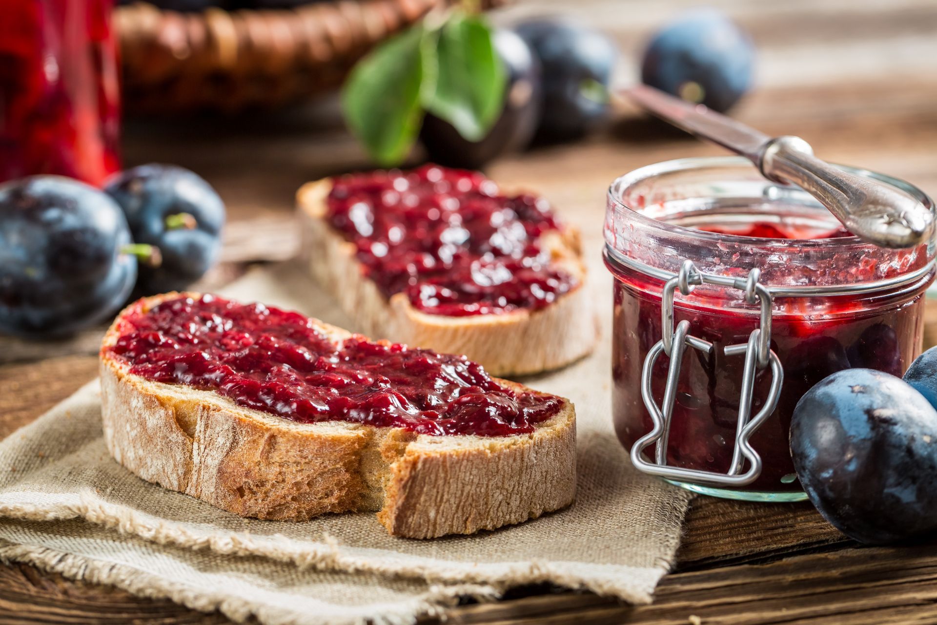 Tartine de confiture rouge à côté d'un pot de confiture sur une table en bois