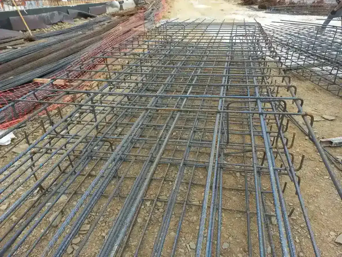 Pilas de varillas de acero en un entorno de almacén, con un fondo borroso y una iluminación cálida.