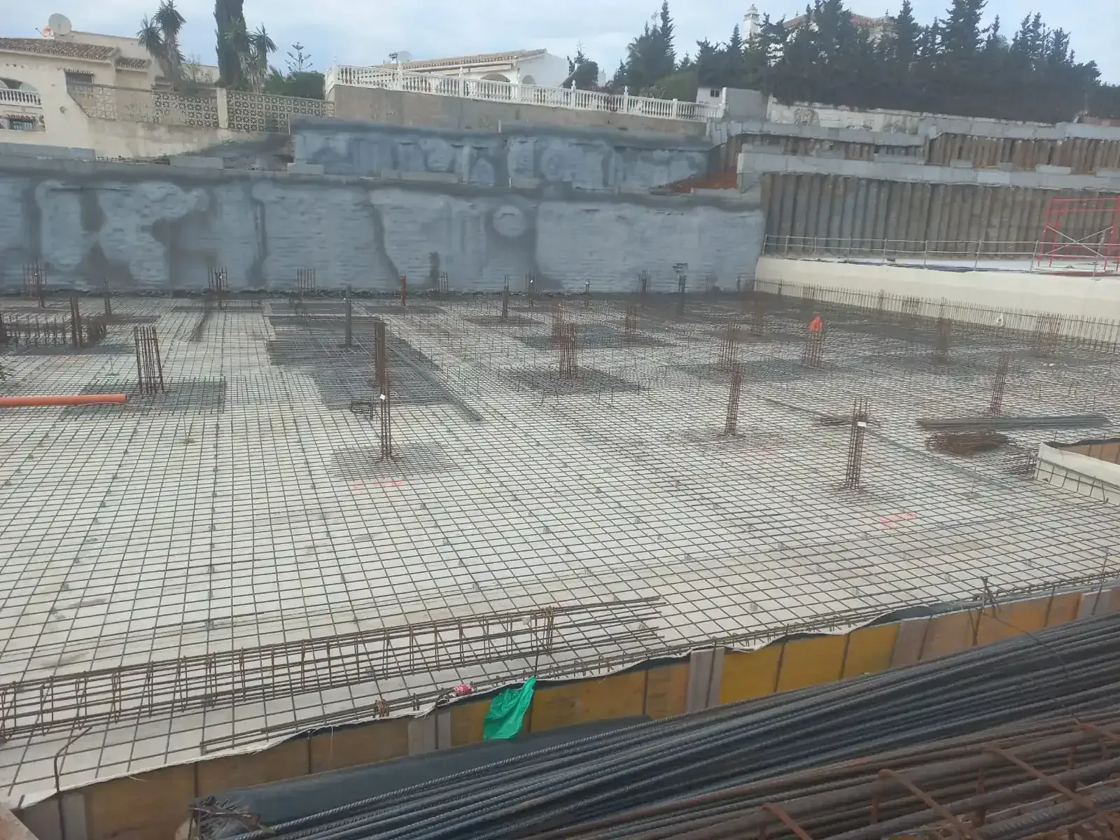 Pilas de varillas metálicas cilíndricas, cuyo color varía desde el gris hasta el óxido, en un entorno de almacén.