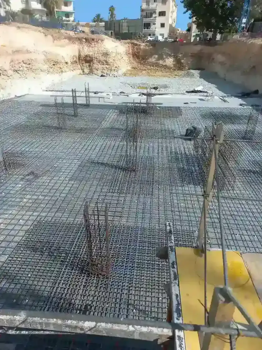 Muro de ladrillos en construcción con barras de refuerzo expuestas contra un cielo azul.