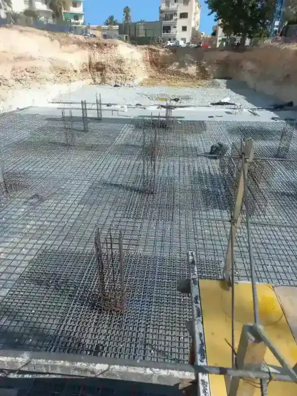 Muro de ladrillos en construcción con barras de refuerzo expuestas contra un cielo azul.