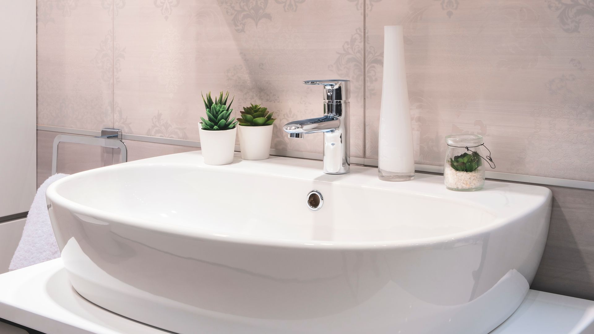 Un lavabo blanc avec des plantes artificielles