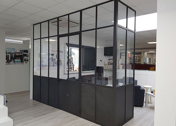Salle de conférence de bureau cloisonnée en verre avec encadrement noir dans un espace de travail ouvert et lumineux
