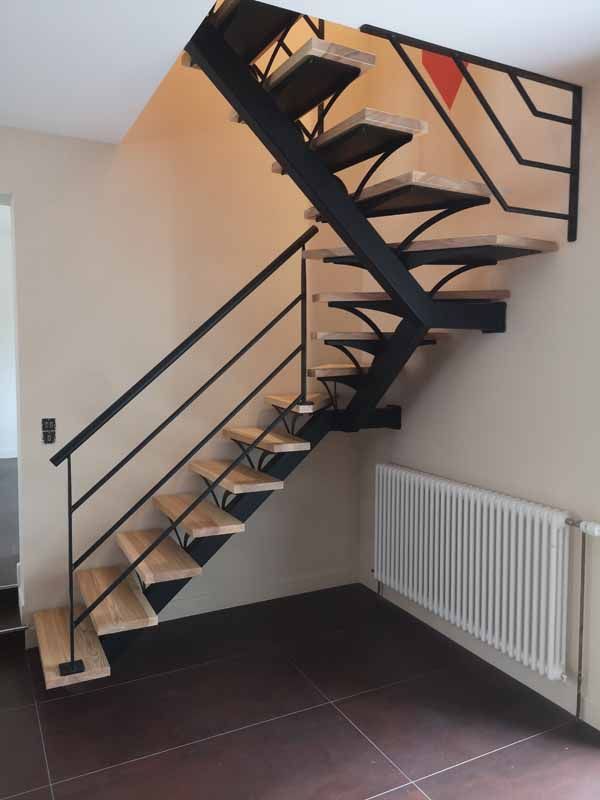 Escalier moderne en métal noir avec marches en bois, dans un coin à côté d'un radiateur blanc.