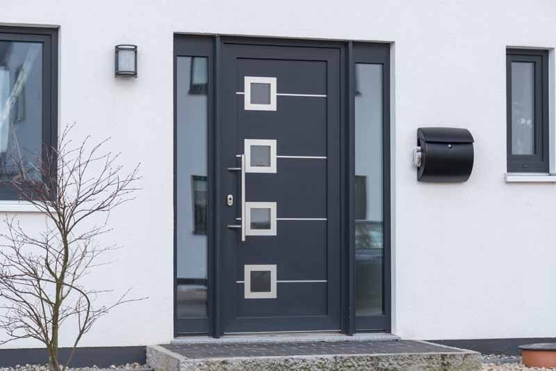 Porte d'entrée moderne avec panneaux de verre carrés sur une façade de maison blanche