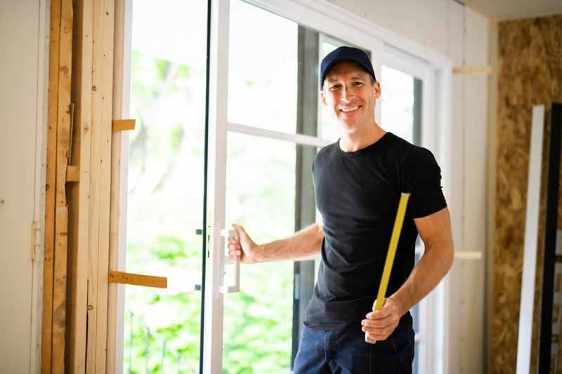 Un homme tenant un mètre ruban dans une pièce lumineuse lors de travaux de rénovation intérieure