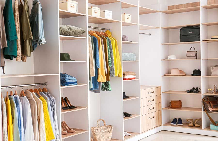 Dressing lumineux avec étagères blanches, vêtements suspendus, chaussures et tiroirs