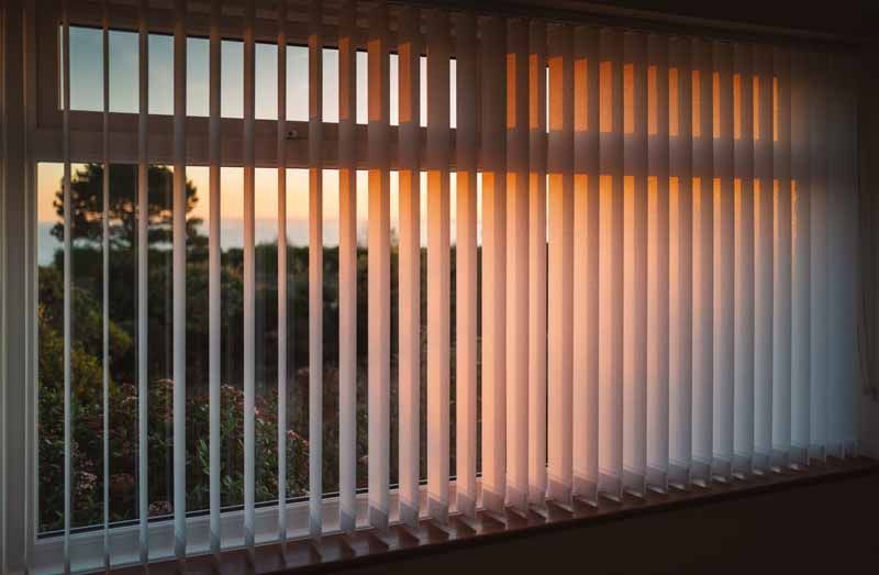 Stores éclairés par la douce lumière du coucher de soleil, avec vue sur les arbres à l'extérieur