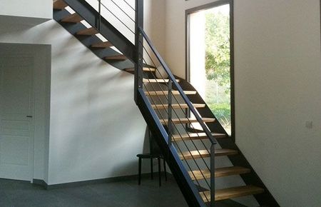 Intérieur moderne avec escalier ouvert, haute fenêtre et murs blancs