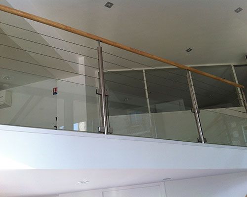 Balcon intérieur moderne avec garde-corps en verre et main courante en bois dans un atrium lumineux