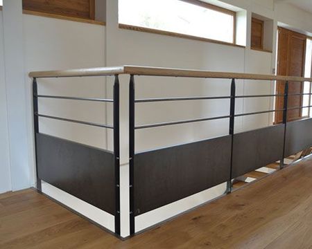 Palier d'escalier moderne avec rampe en métal noir et blanc dans un couloir intérieur lumineux
