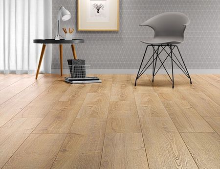 Pièce moderne et lumineuse avec parquet clair, chaise grise, table d'appoint, lampe et tableau encadré.