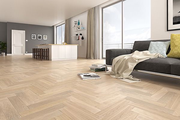 Salon moderne et lumineux avec parquet à chevrons, canapé gris et grandes fenêtres