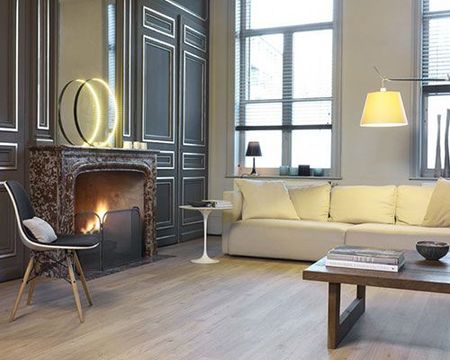 Salon moderne avec canapé crème, cheminée, suspension lumineuse et grandes fenêtres