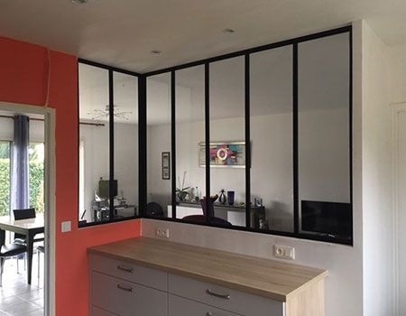 Passe-plat moderne avec panneaux de verre à cadre noir au-dessus d'un plan de travail en bois clair.