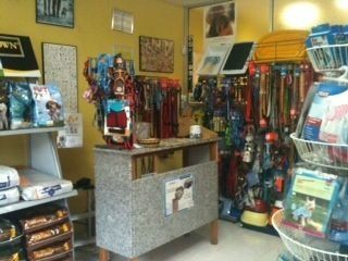 Interior de una tienda de mascotas, con alimentos para perros, correas, arneses y accesorios en estantes y vitrinas.