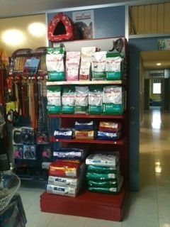 Expositor de alimentos para mascotas en una tienda, con varios productos envasados ​​en estantes. Soporte rojo, productos apilados.