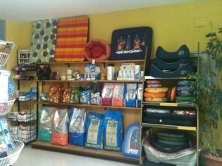 Estanterías en una tienda de mascotas que exhiben camas para perros, comida y productos de aseo.