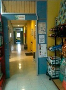 Entrada al pasillo, marco de puerta azul, paredes amarillas, estanterías a la derecha.