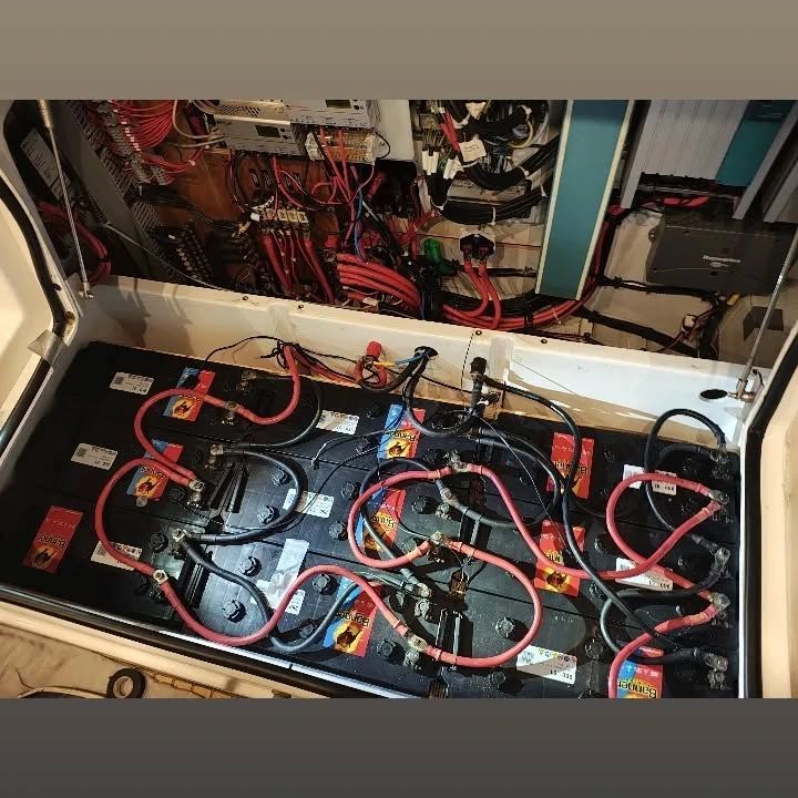 Sistema eléctrico de embarcación con múltiples baterías, cables rojo y negro y varios componentes.