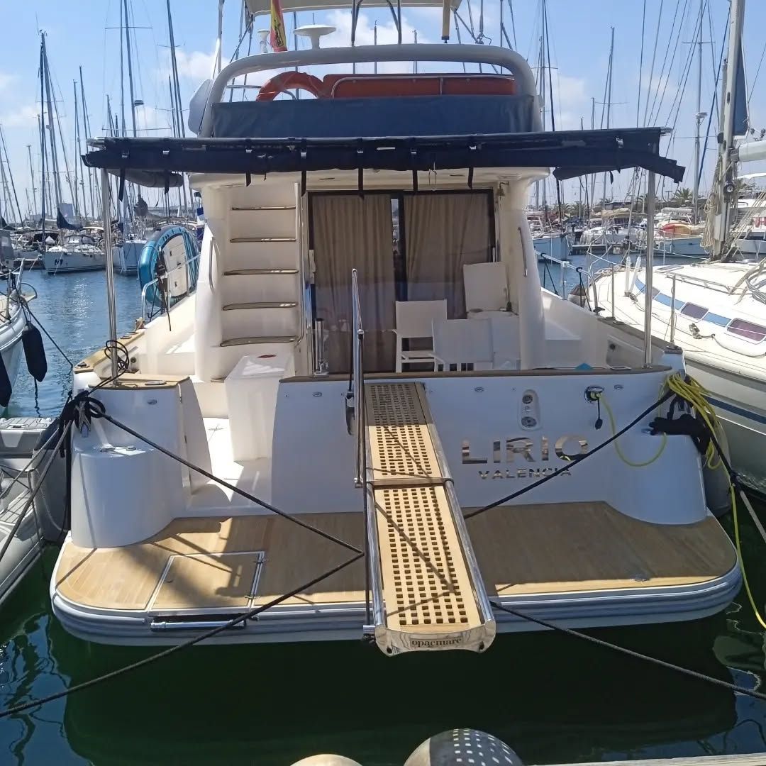 Vista trasera de un yate blanco con una rampa que se adentra en el agua. 