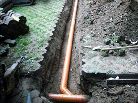 In einem Graben im Erdreich wird ein Rohr verlegt.