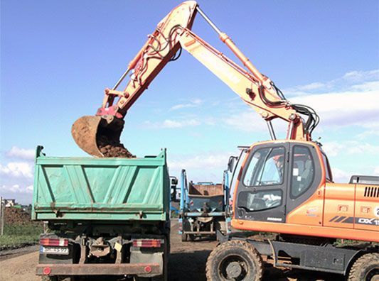 Ein Bagger lädt Erde in einen Muldenkipper