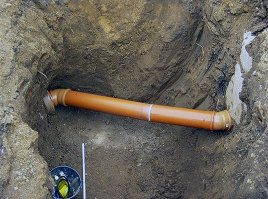 In einem Loch im Boden wird ein Rohr installiert.