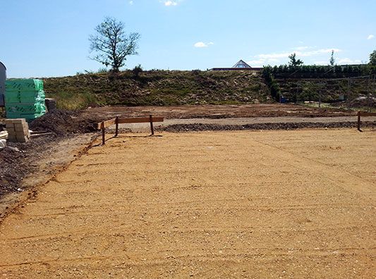 Ein Feld aus Erde mit einem Zaun und einem Baum im Hintergrund.