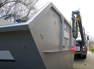 Ein Müllcontainer wird von einem LKW mit dem Buchstaben A auf der Rückseite angehoben