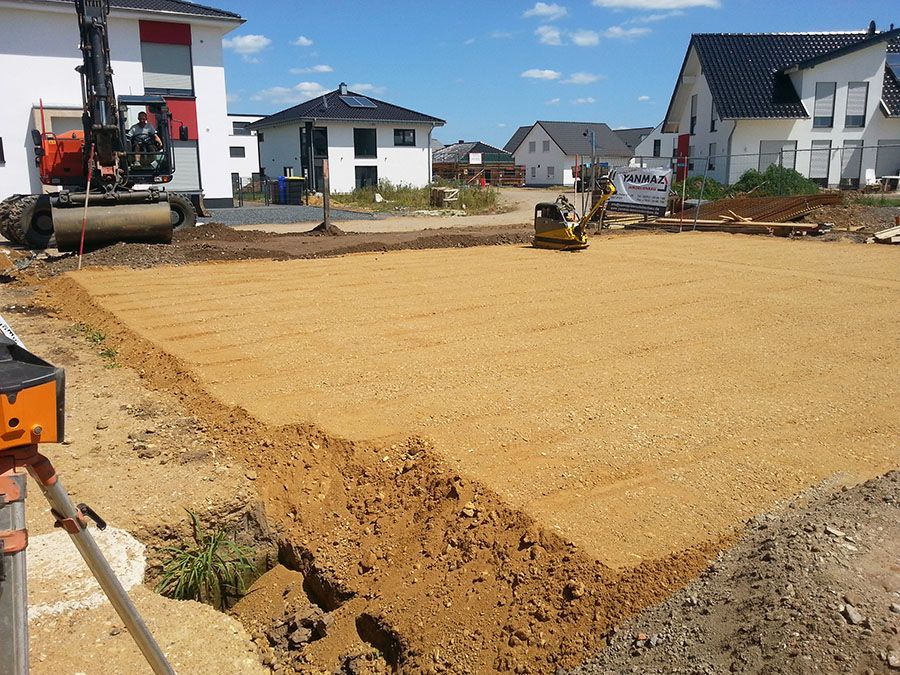 Eine Baustelle mit viel Dreck und Häusern im Hintergrund