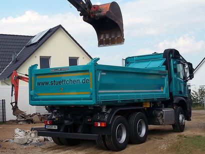 Ein blauer Muldenkipper steht vor einem Haus