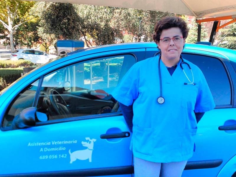 Una mujer con un uniforme azul está parada frente a un auto azul.