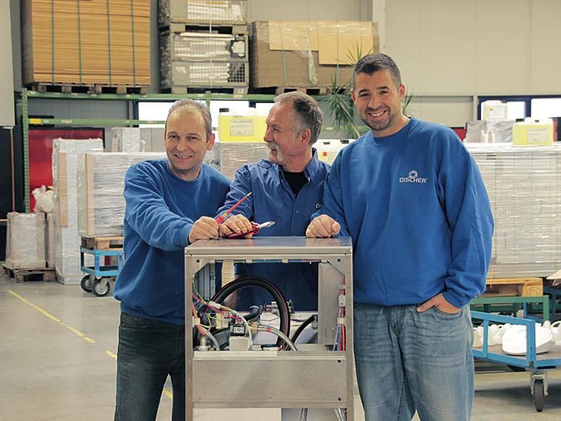 Drei Männer in blauen Sweatshirts arbeiten an einer Maschine