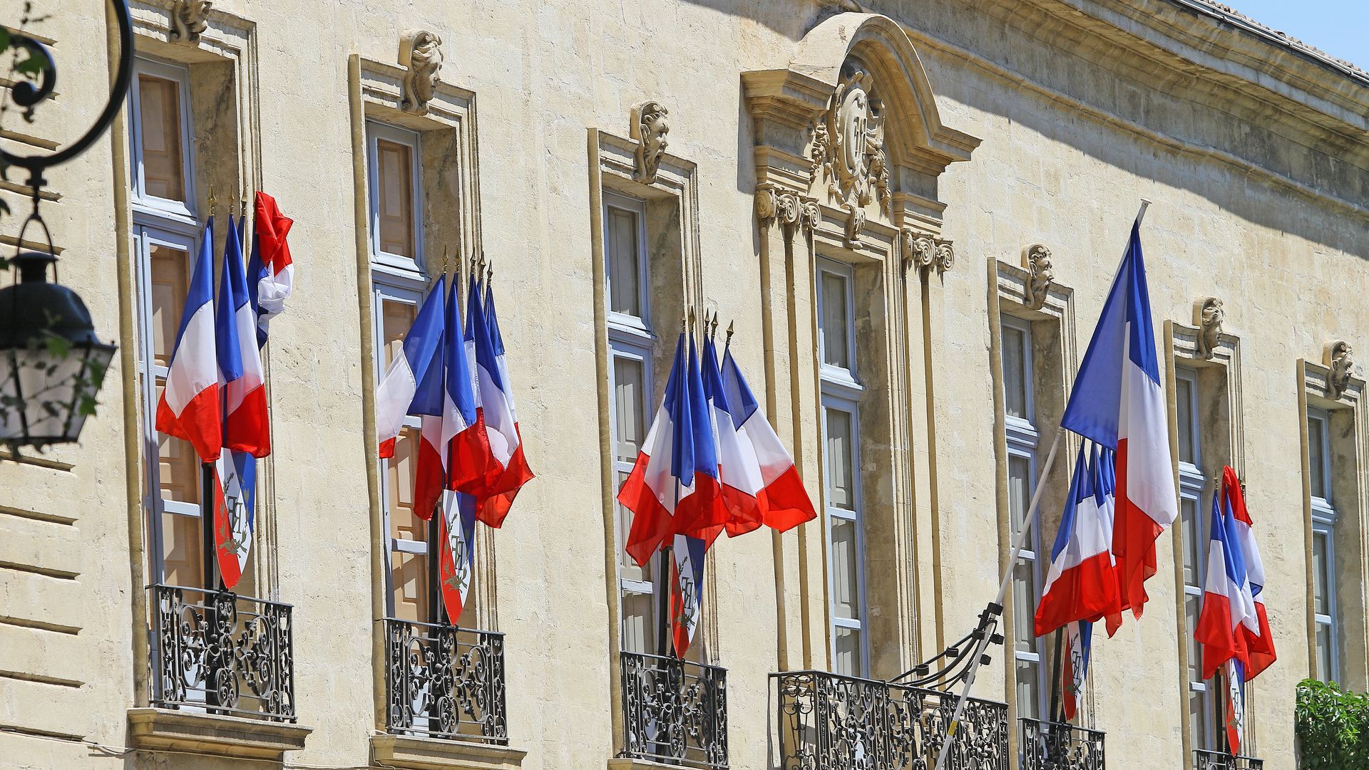 Drapeaux français suspendus aux fenêtres d’une façade en pierre