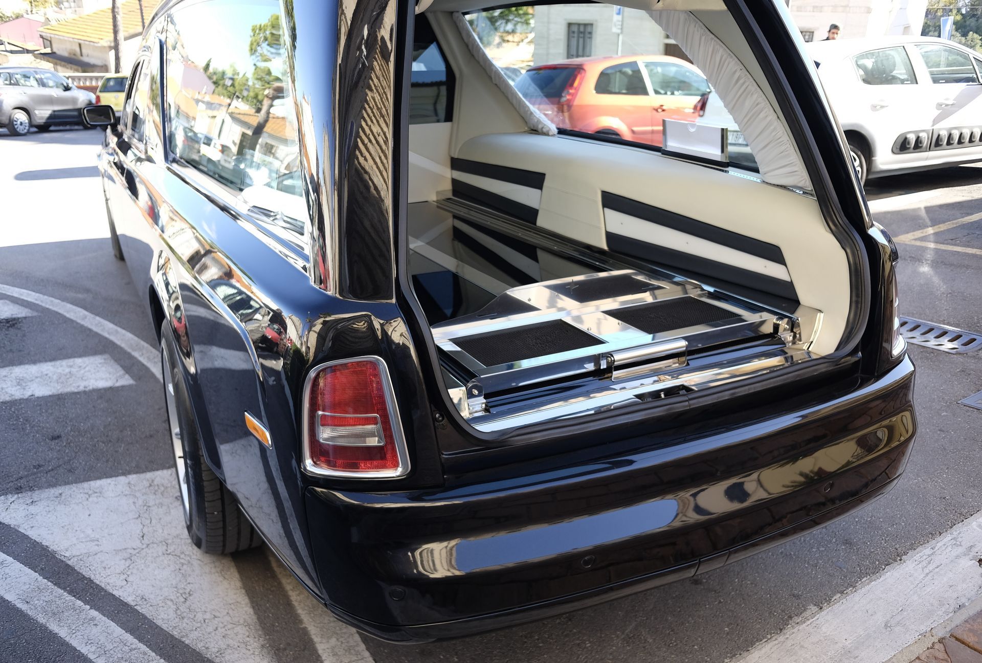 Coffre ouvert d'un corbillard noir garé sur un parking en extérieur