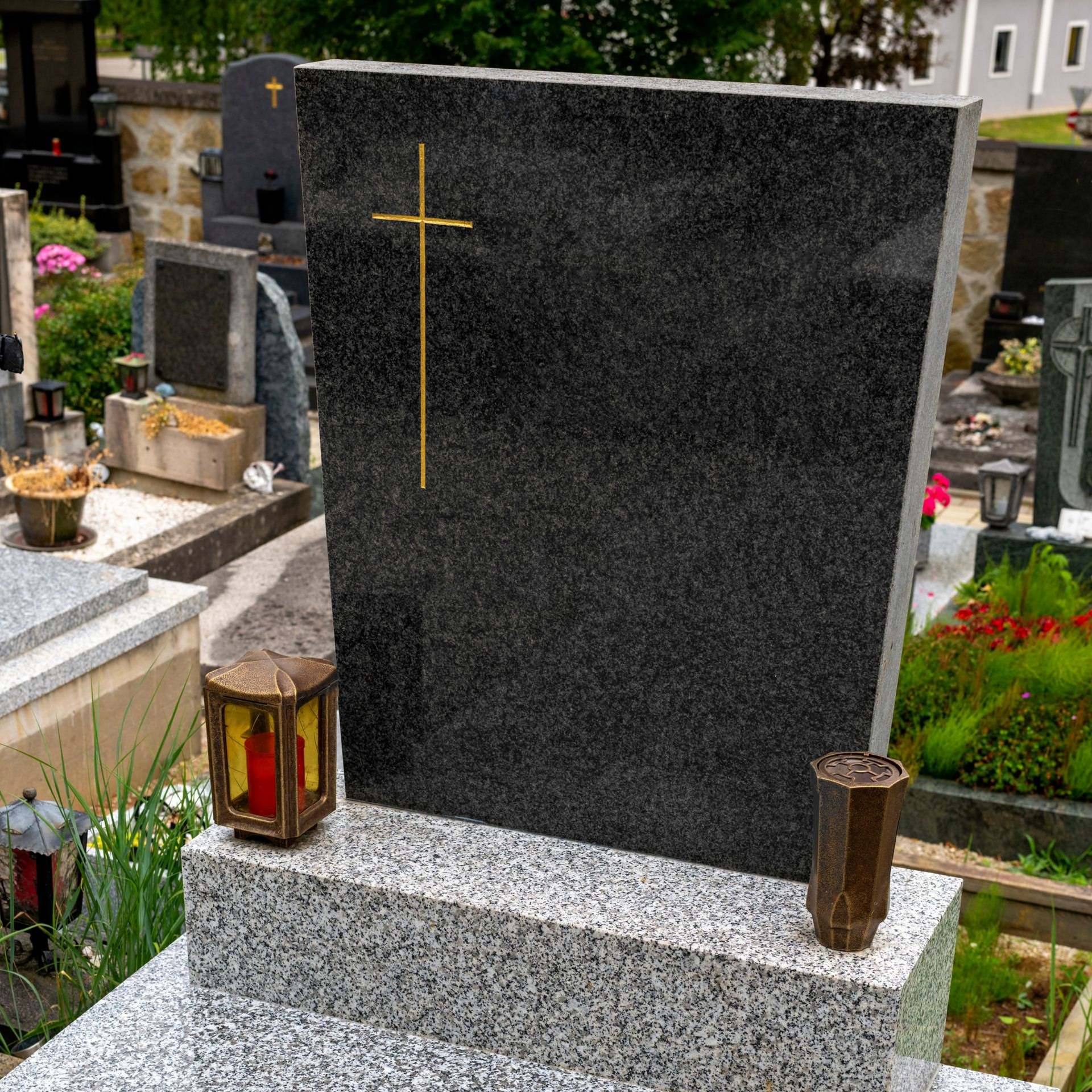 Pierre tombale en granit noir ornée d’une croix dorée dans un cimetière