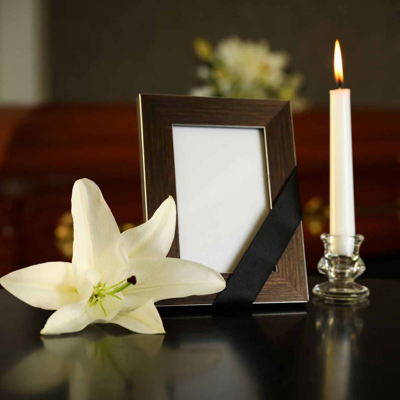 Lys blanc, cadre photo vide et bougie allumée sur une table commémorative