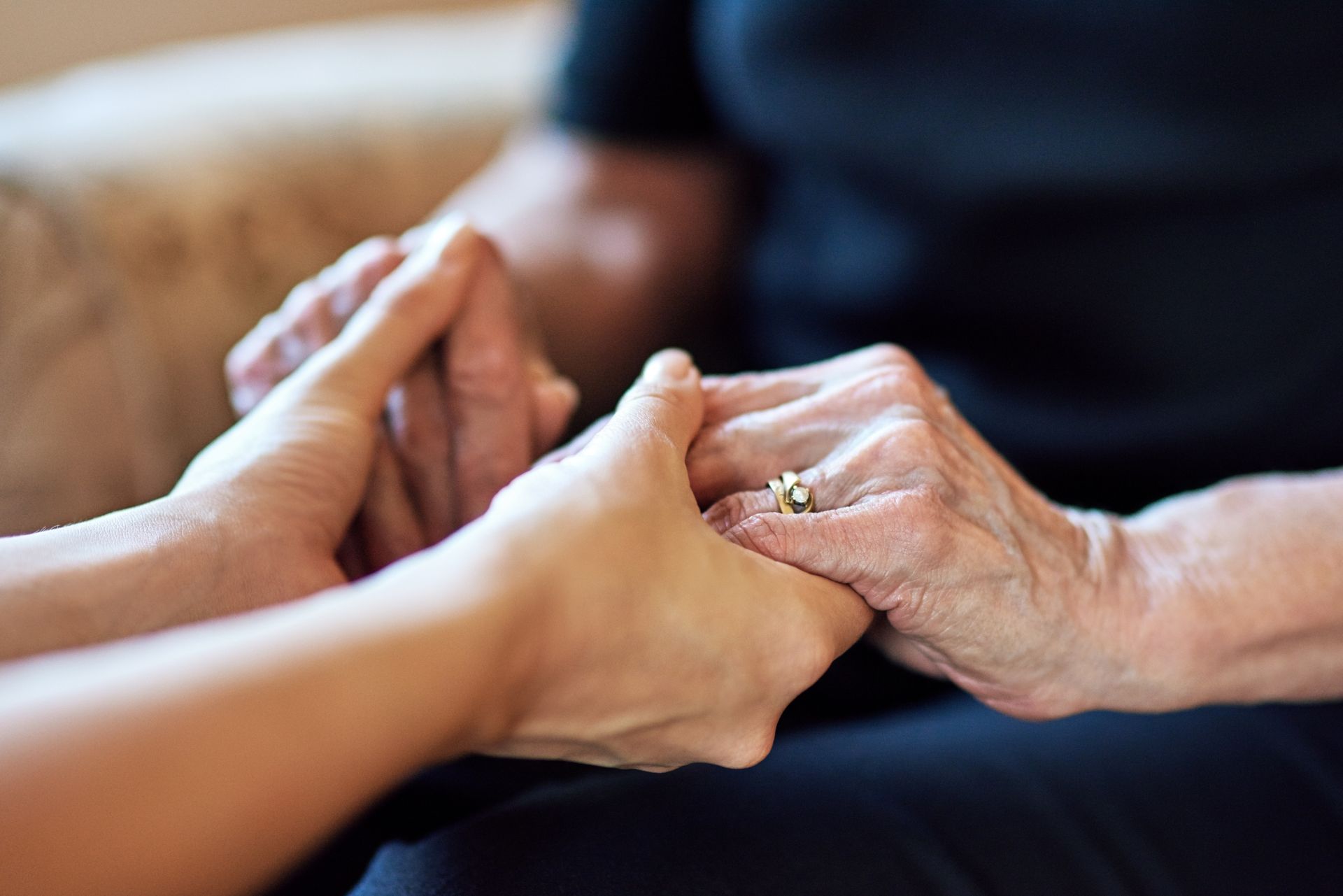 Gros plan de deux personnes se tenant les mains, assises sur un canapé