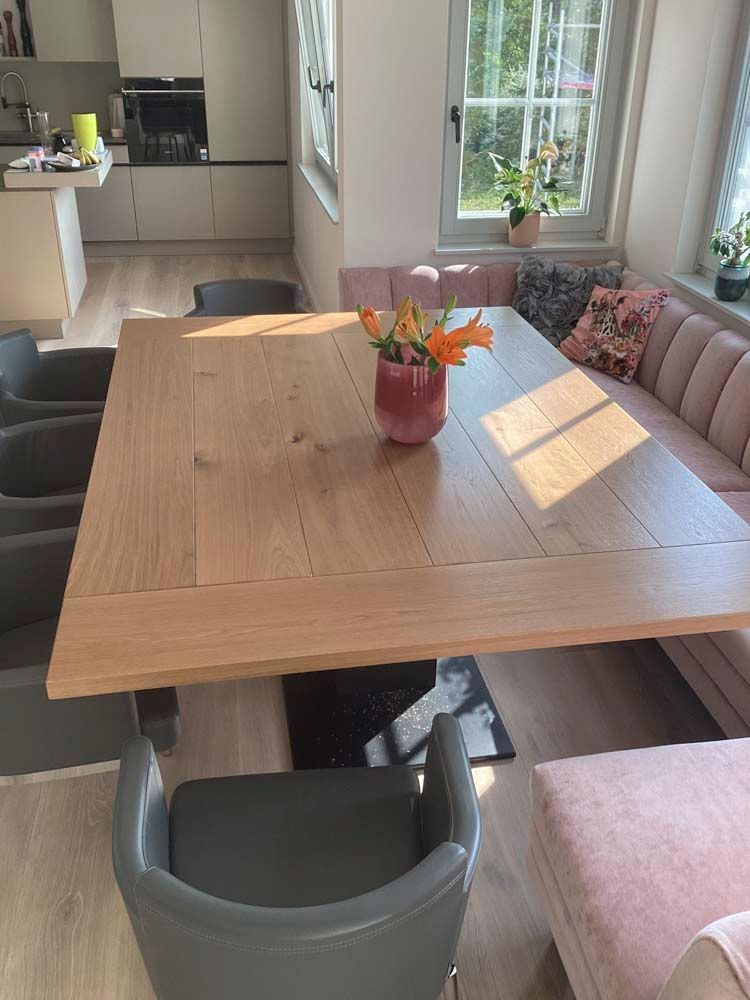 Ein Holztisch mit einer Blumenvase darauf in einem Wohnzimmer.