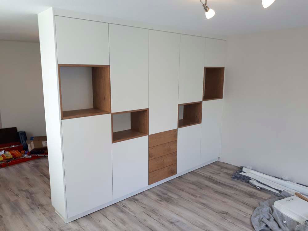 Ein Raum mit weißen Schränken und Holzregalen.