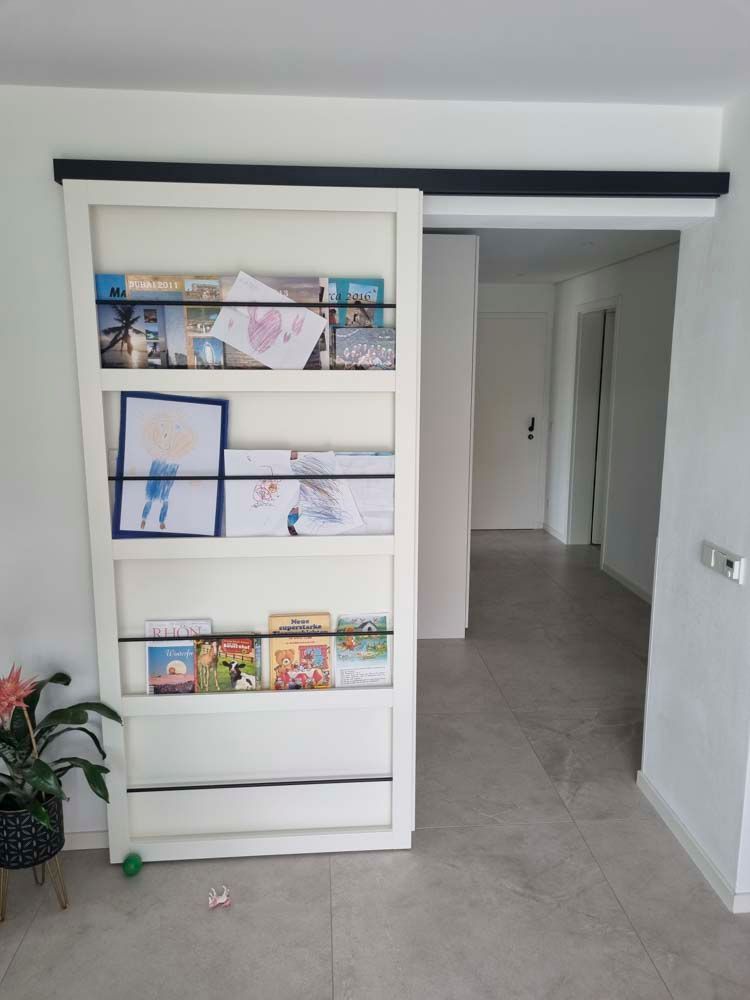 Ein Bücherregal mit Büchern und Bildern in einem Flur.