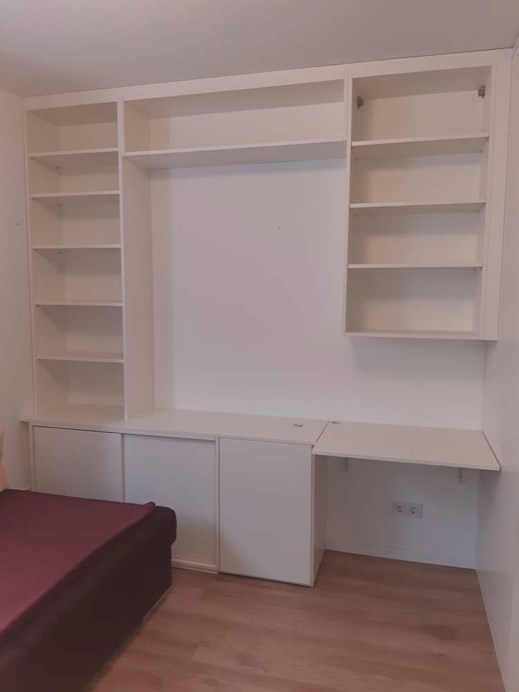 Ein Schlafzimmer mit Bett, Regalen und Schreibtisch.