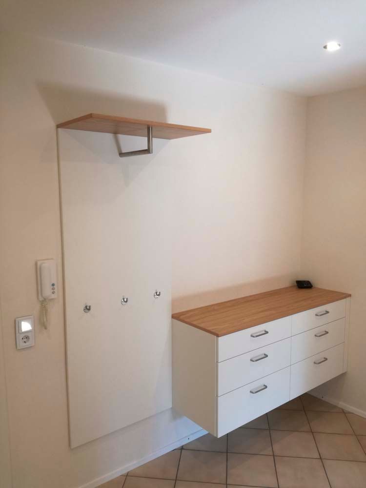 Ein Flur mit einer weißen Kommode und einem Holzregal.