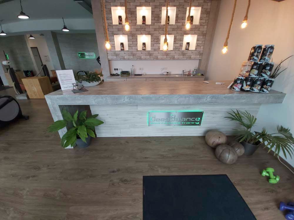 Ein Empfangstresen in einem Fitnessstudio mit Pflanzen und Hanteln auf dem Boden.