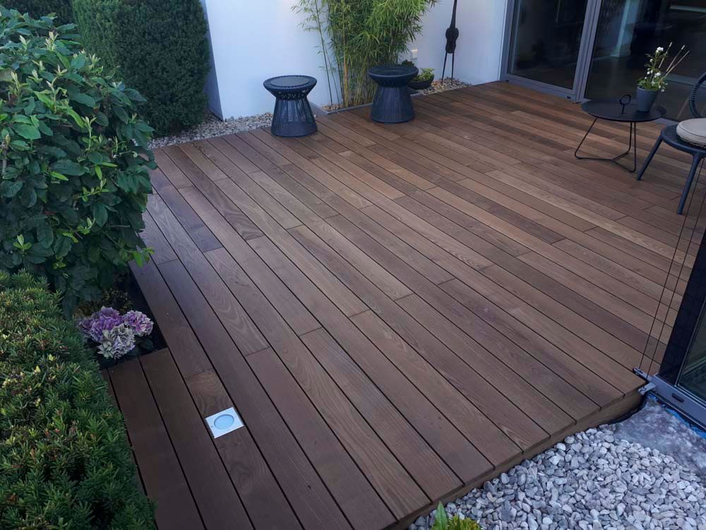 Eine Holzterrasse mit Hockern und Stühlen darauf