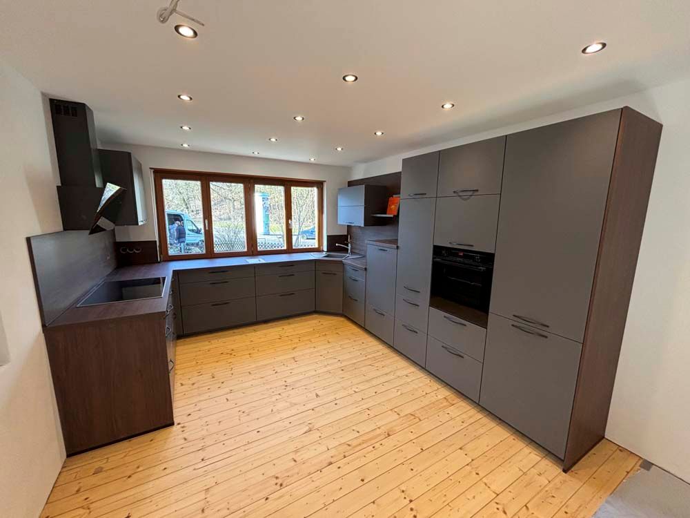 Eine Küche mit Holzböden und grauen Schränken