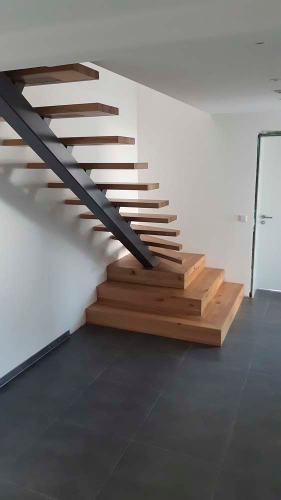 Eine Holztreppe mit einem Metallgeländer befindet sich in einem leeren Raum.